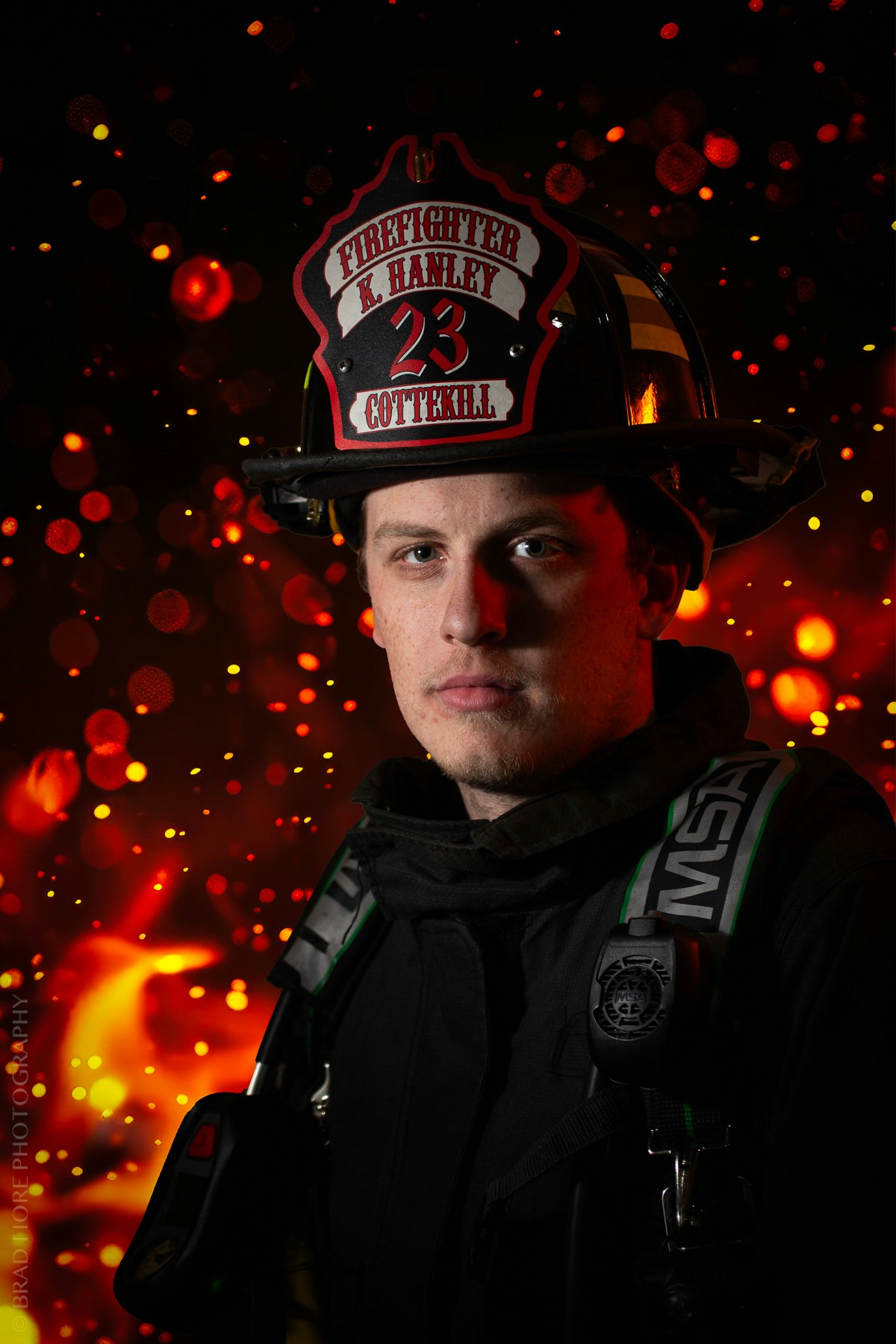 A firefighter in uniform, with a helmet labeled "K. Hanley, Cottlekill 23," stands against a fiery backdrop with glowing embers.
