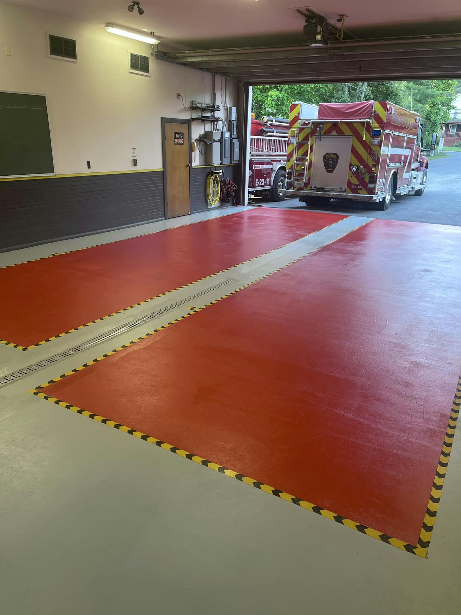 An interior view of a fire station with a fire engine exiting the garage.