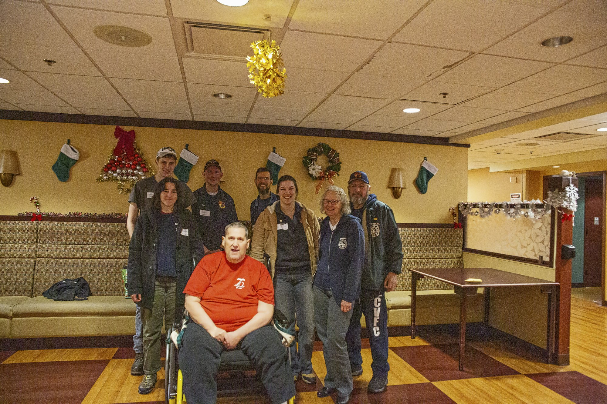 Group of people posing in a room with festive decorations, including Christmas stockings and wreaths.