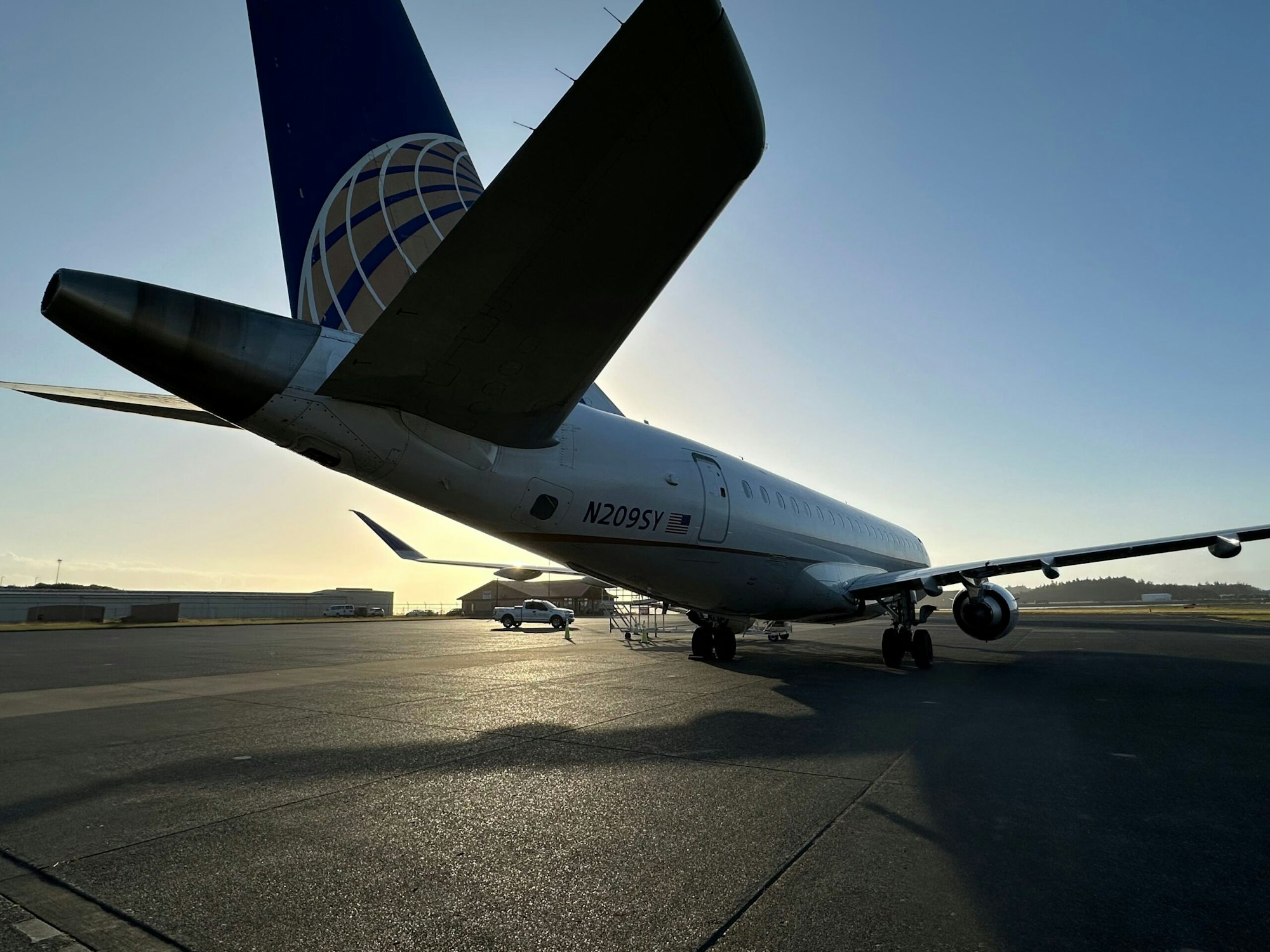 An airplane on the tarmac at sunset, with the sun casting long shadows.