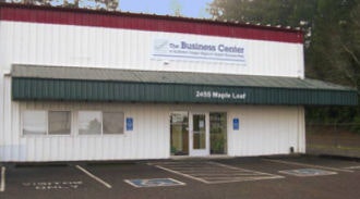 A commercial building with a sign "The Business Center" and parking spaces, including handicap spots, in front.