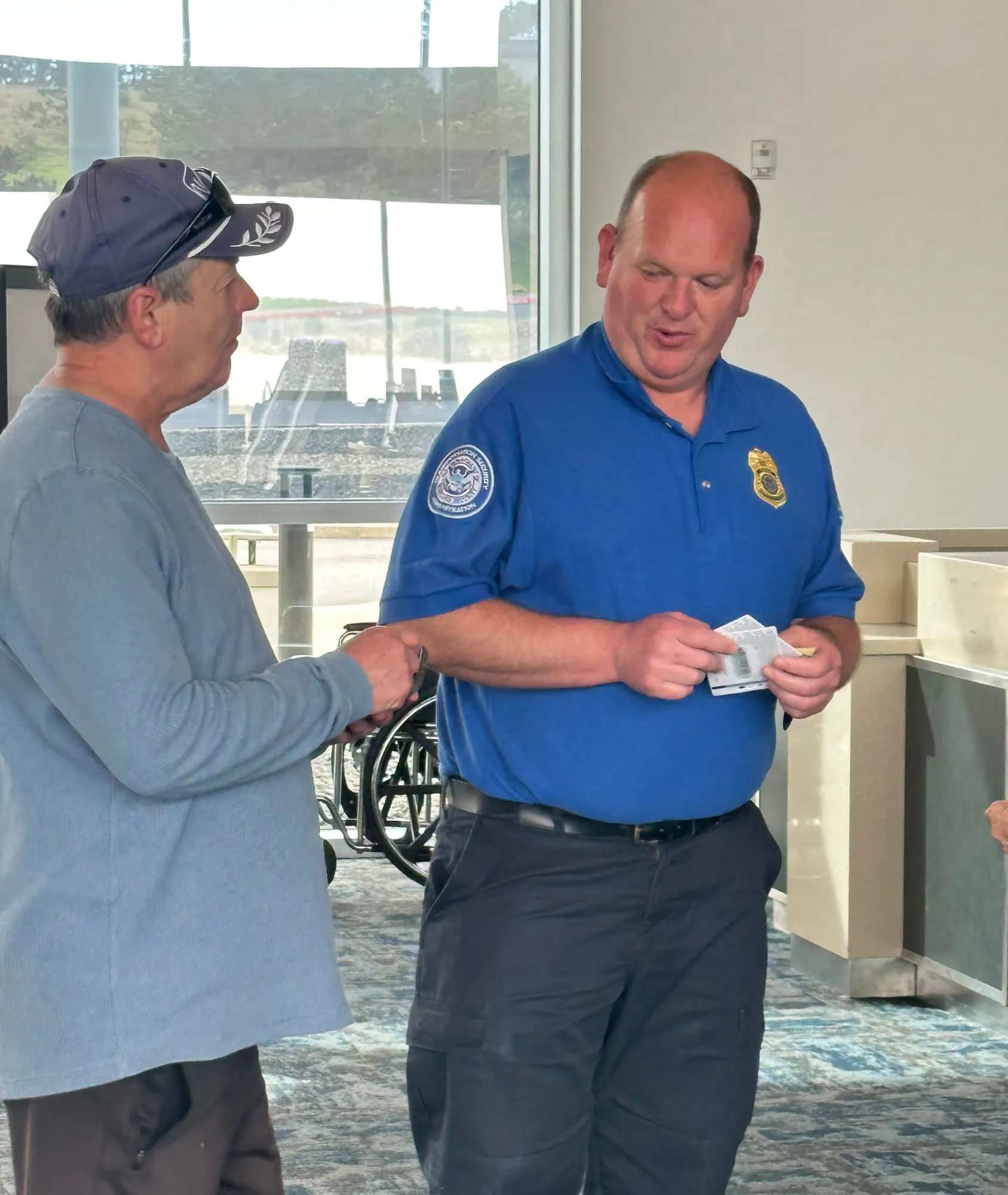 Two men are engaged in a conversation, with one wearing a blue uniform and the other in casual attire.