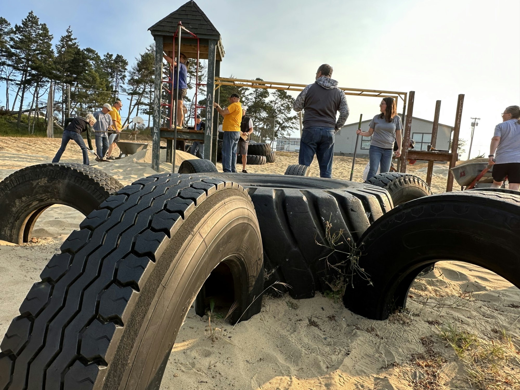 A playground with buried tires and people in the background.