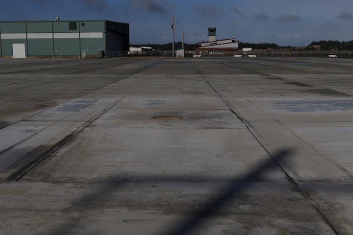 Empty airport apron, hangar, control tower, shadow of aircraft's tail.