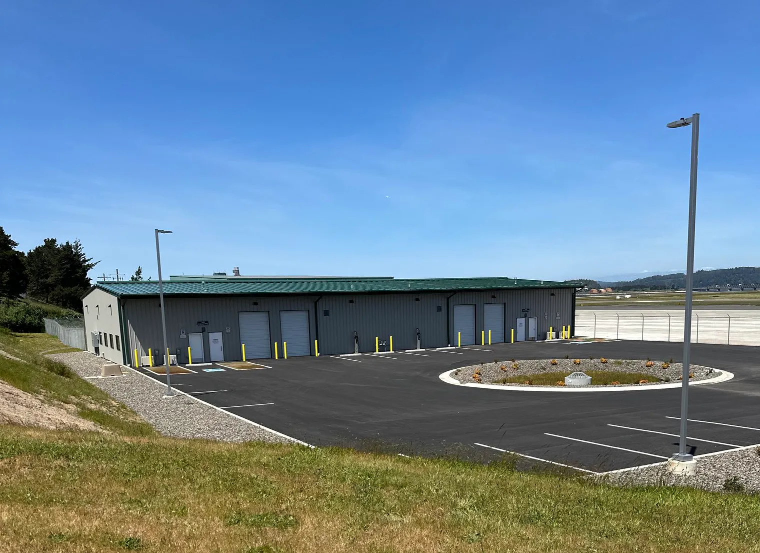 A single-story cargo building at the Southwest Oregon Regional Airport, surrounded by a paved area, grass, and clear blue sky.