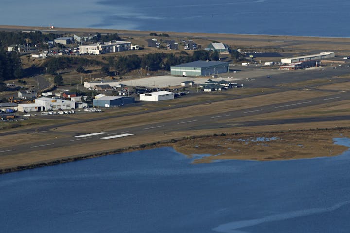 Aerial view of an airport with adjacent buildings, runways, and surrounding water.
