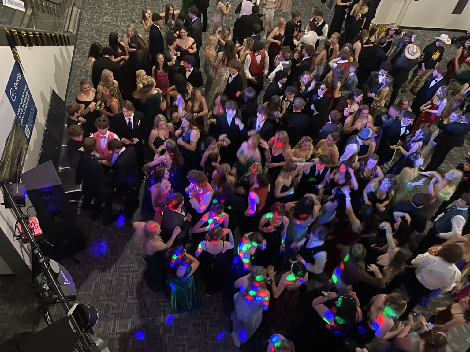 A lively dance floor with people in formal attire, some with glowing accessories.