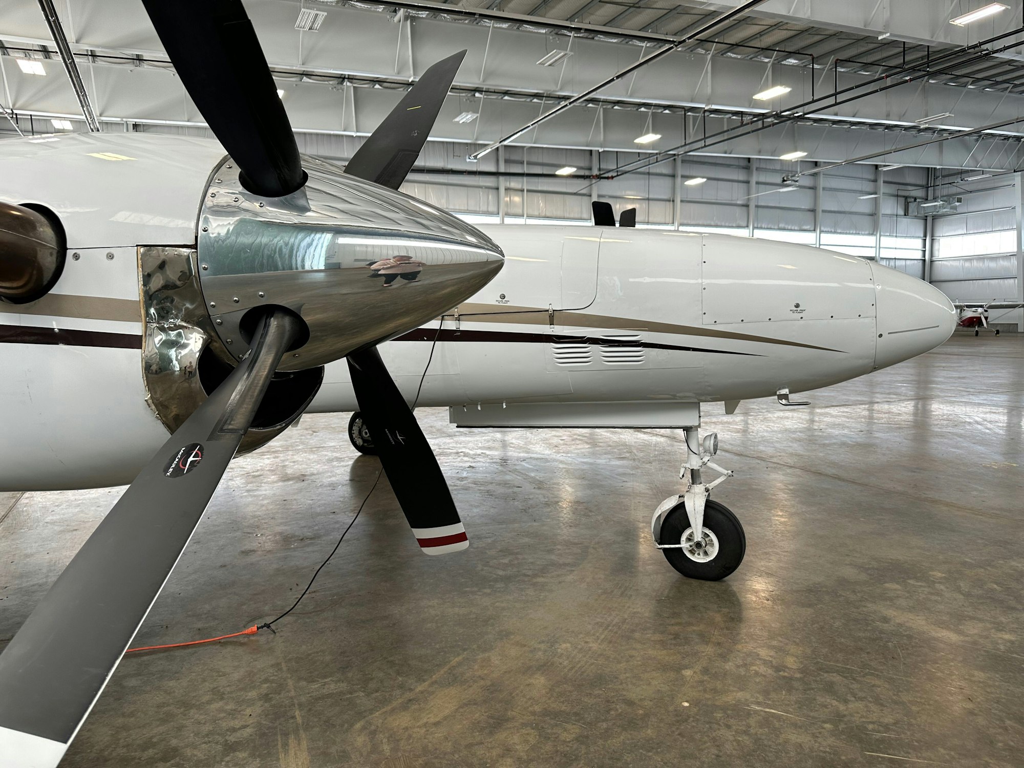 Close-up of an aircraft's propeller and landing gear in a hangar.