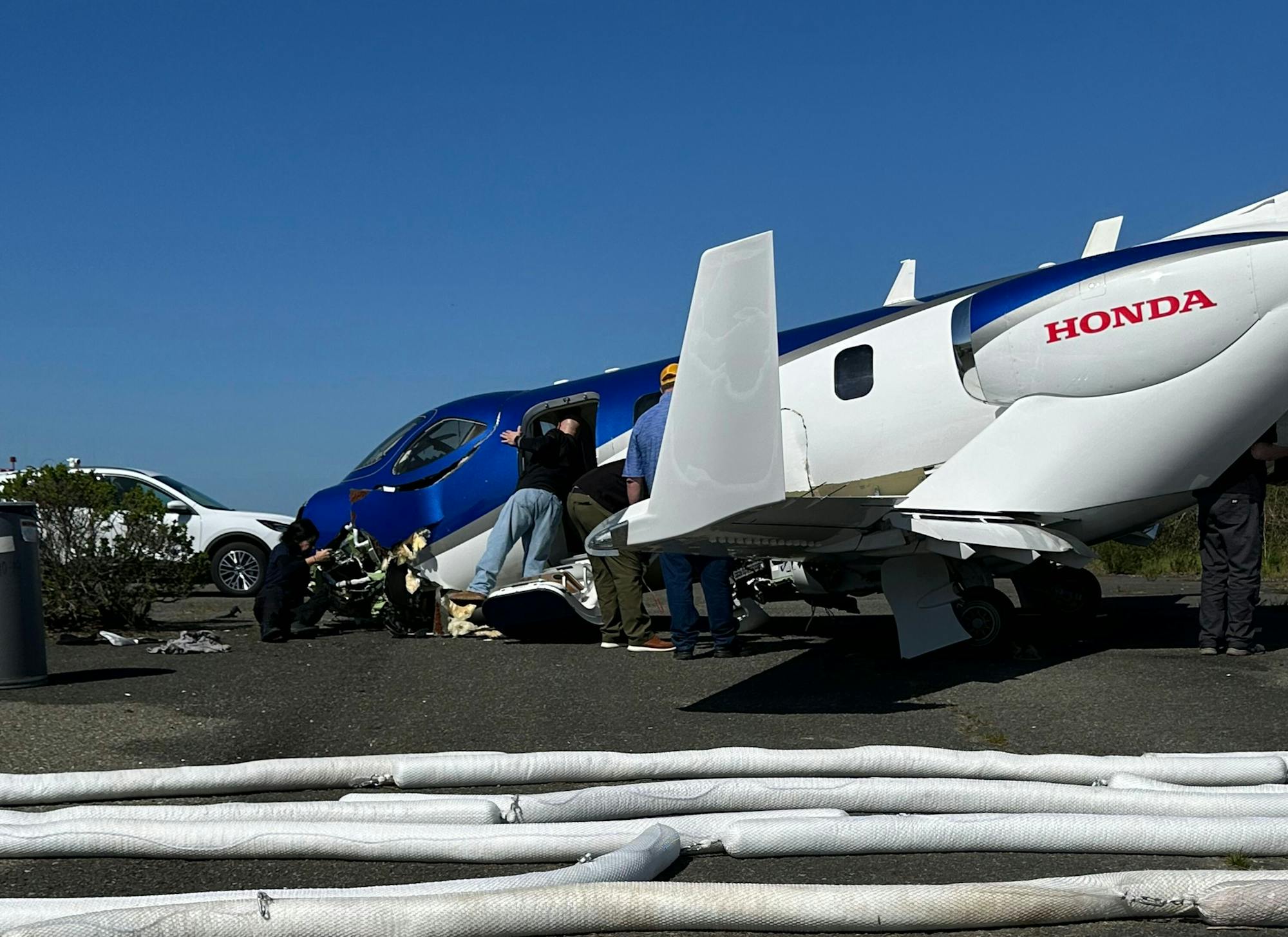 A small aircraft with people around it on the ground, surrounded by several white cylindrical objects.
