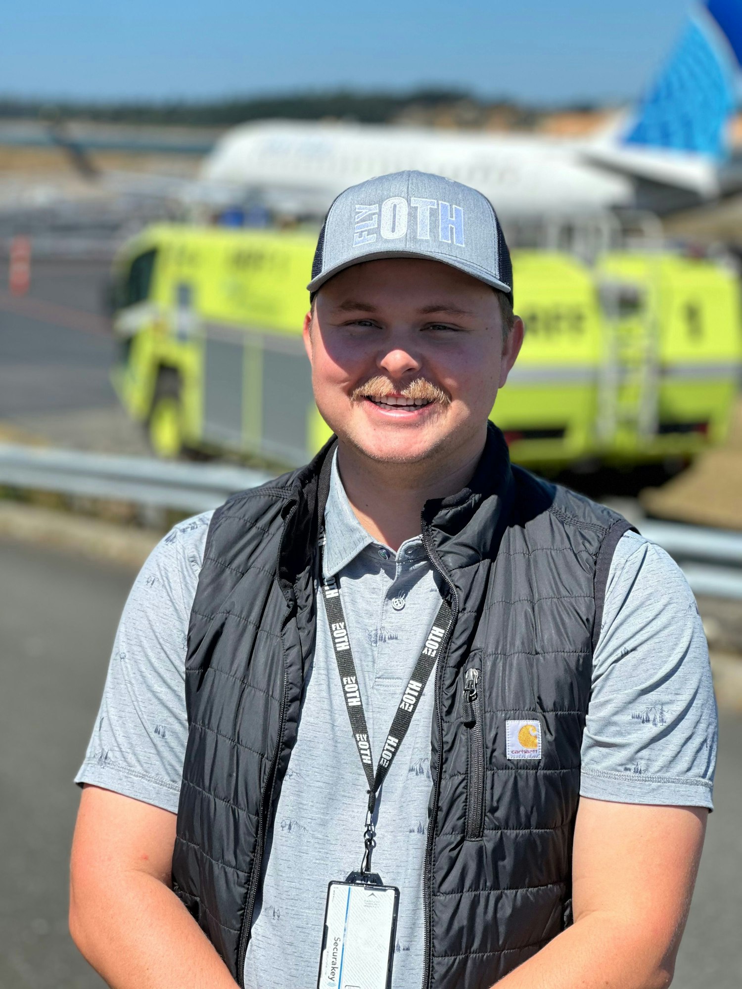 Will Perez, OTH's newest team member, with the ARFF fire truck and an airplane in the background.