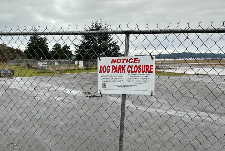 Chain-link fence with a "Dog Park Closure" notice.