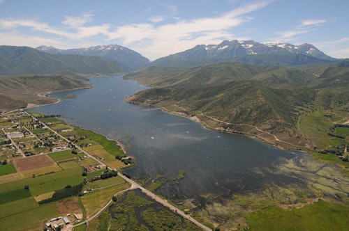 Aerial view of a serpentine river with surrounding greenery and mountains in the background.
