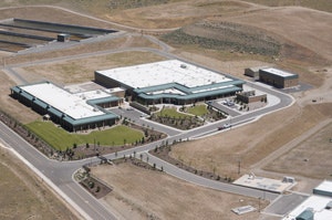 Aerial view of a modern facility with multiple buildings, landscaping, and a parking area in a sparsely populated region.