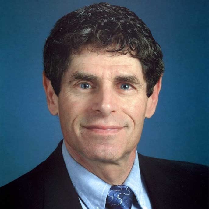 A man in a business suit with a blue background.