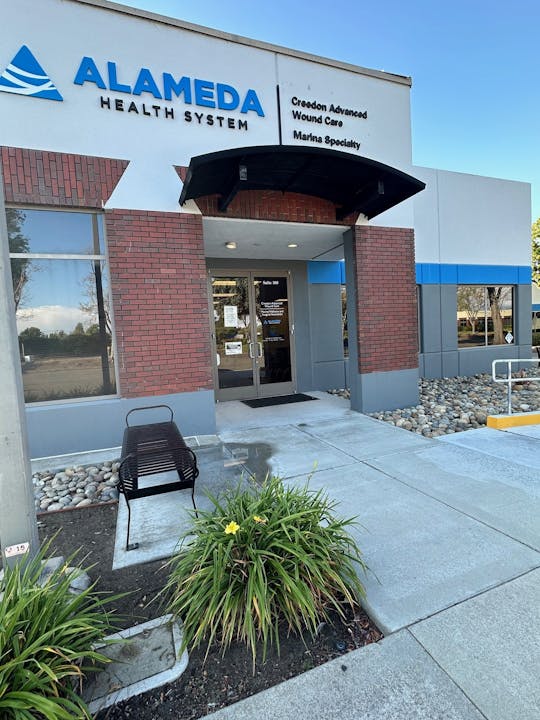 An exterior view of Alameda Health System building with signage for advanced wound care and specialty services.