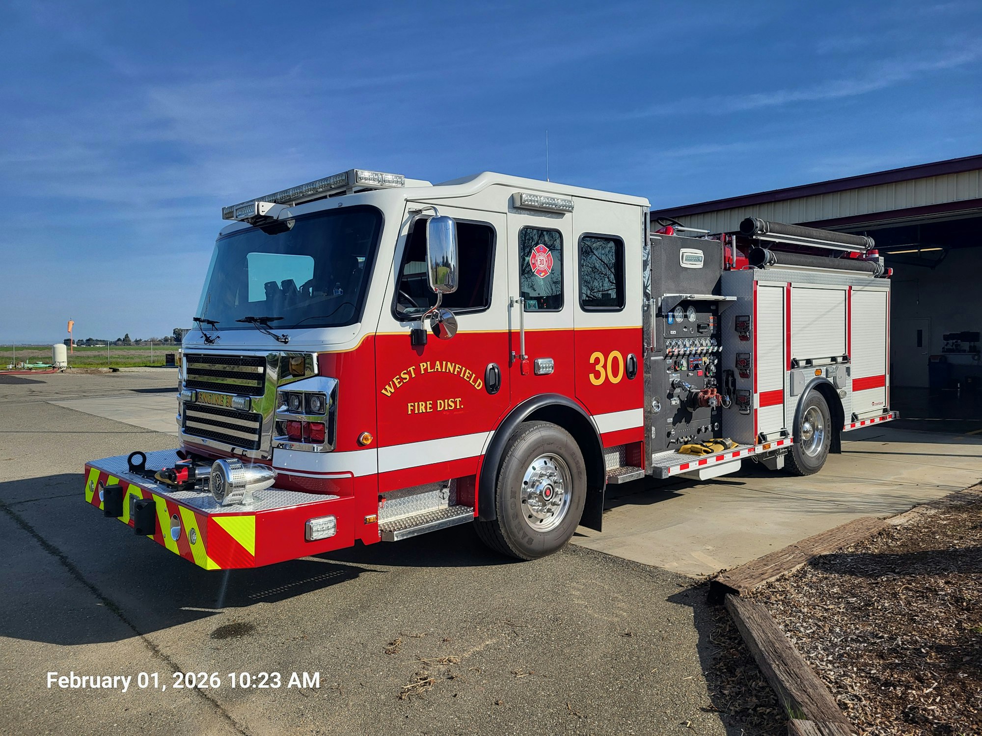 The image shows a red and white fire truck with "West Plainfield Fire Dist." written on it, parked outside a fire station.