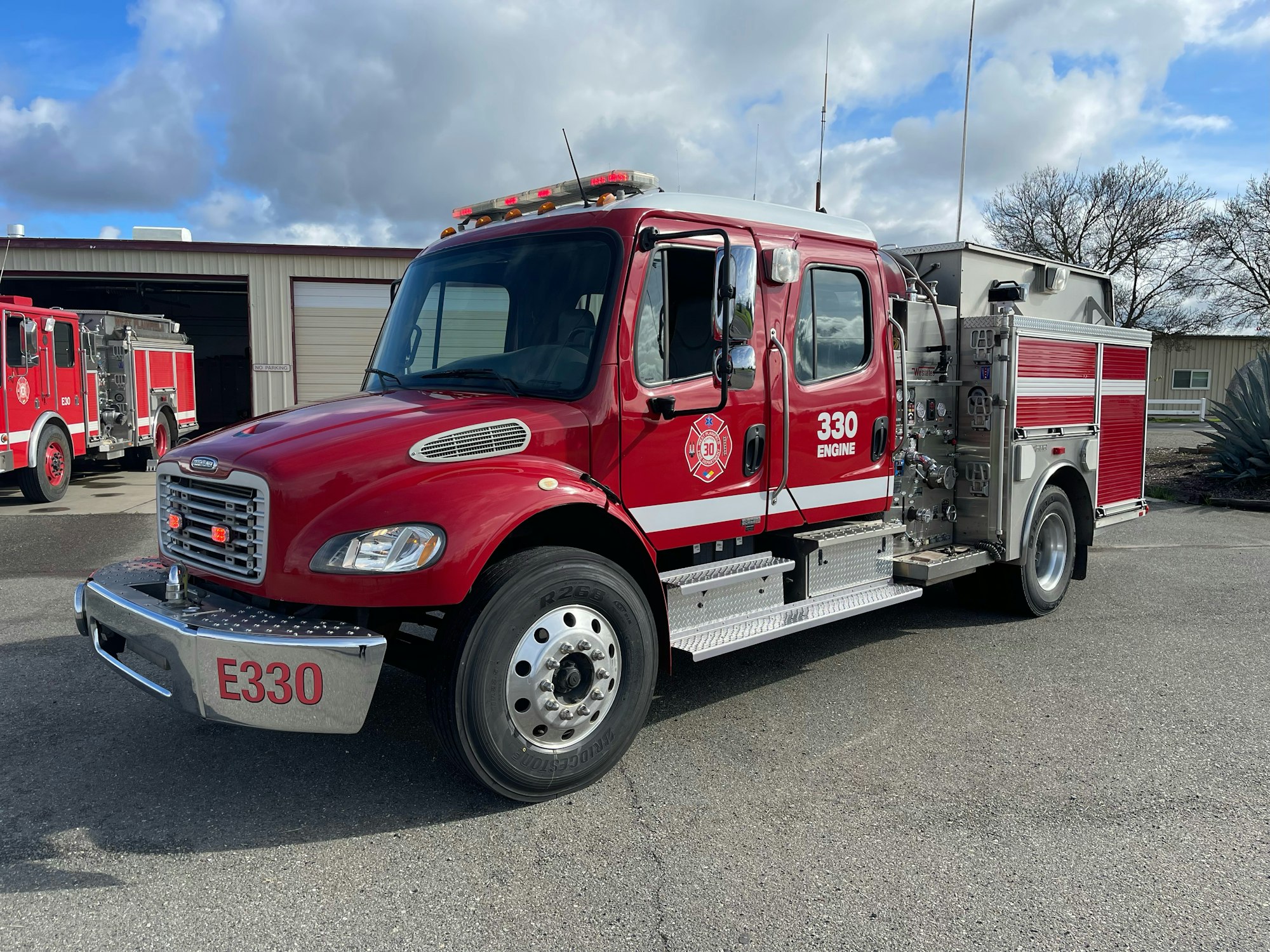 A red fire truck labeled "330 Engine" parked outdoors near a building.