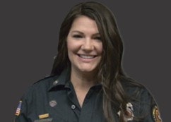 A person in a uniform with badges smiles against a dark background.