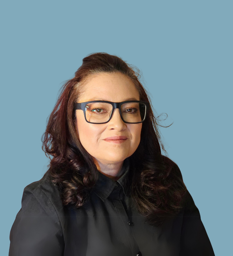 A person with glasses and long hair, wearing a black shirt, on a blue background.