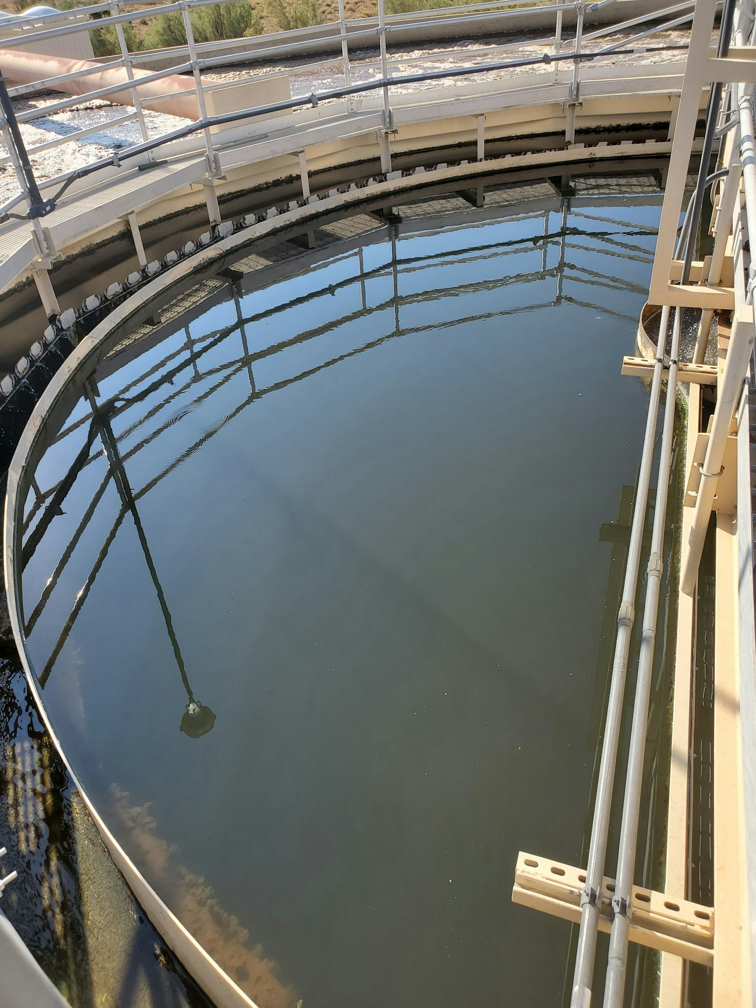 A circular water tank with metal railings and pipes, likely part of a treatment plant.