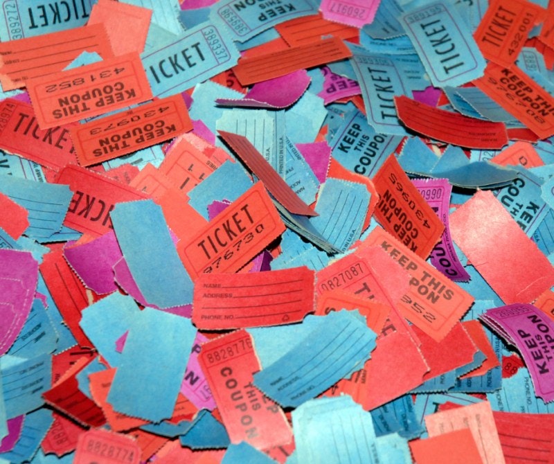 A pile of colorful raffle tickets in red, blue, and purple with various numbers and "KEEP THIS COUPON" text.