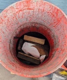 A red bucket containing wooden blocks and a white object inside.