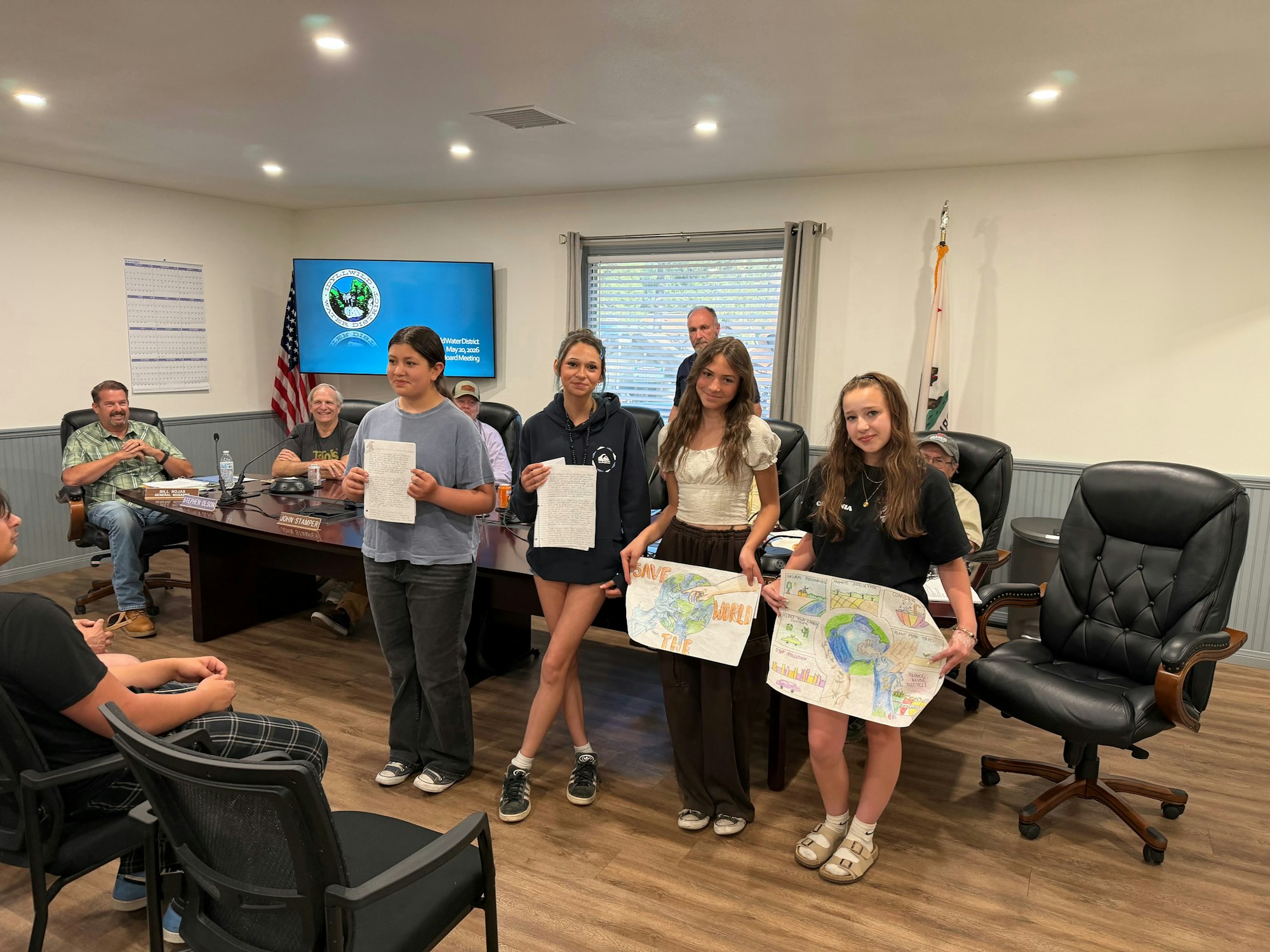 A group of youth present projects or statements at a meeting, advocating for environmental awareness.