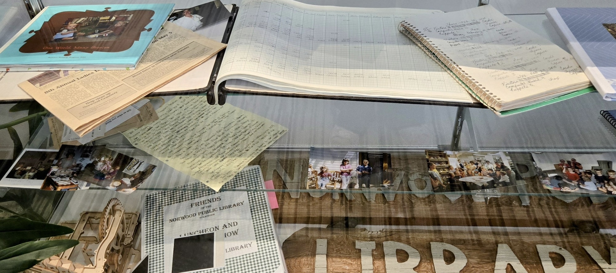 Books, notebooks, photos, and newspaper clippings on a glass table.