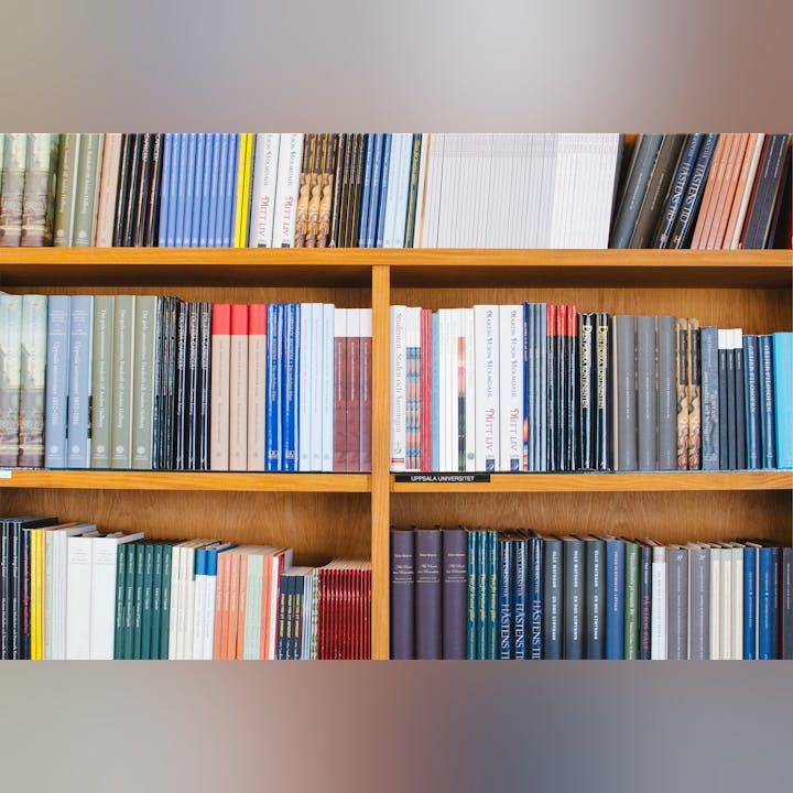 A wooden bookshelf filled with various books, featuring a mix of colors, sizes, and titles, including some academic volumes.