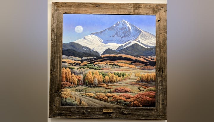 A framed painting depicts a snowy mountain, a colorful autumn forest, and an elk in a vibrant landscape.