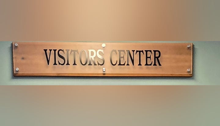 A wooden sign with the text "VISITORS CENTER" on it.