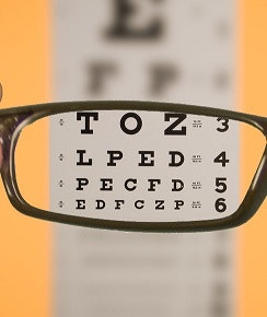 An eye chart viewed through eyeglass lenses, showing clearer vision of the letters.