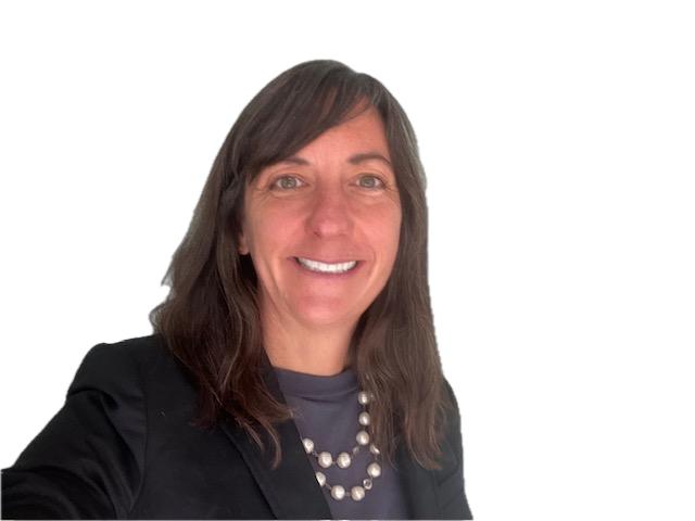 A smiling woman in a black blazer and a pearl necklace poses for the camera against a plain background.