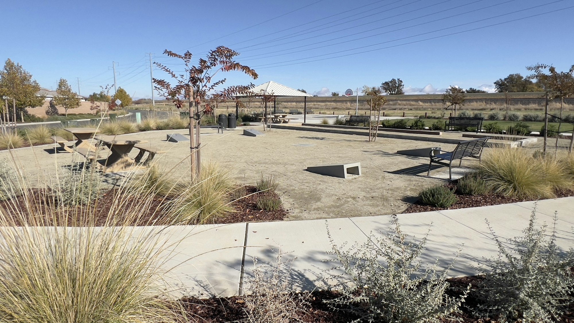 Public park with benches, tables, gazebo, and landscaping under a clear sky.