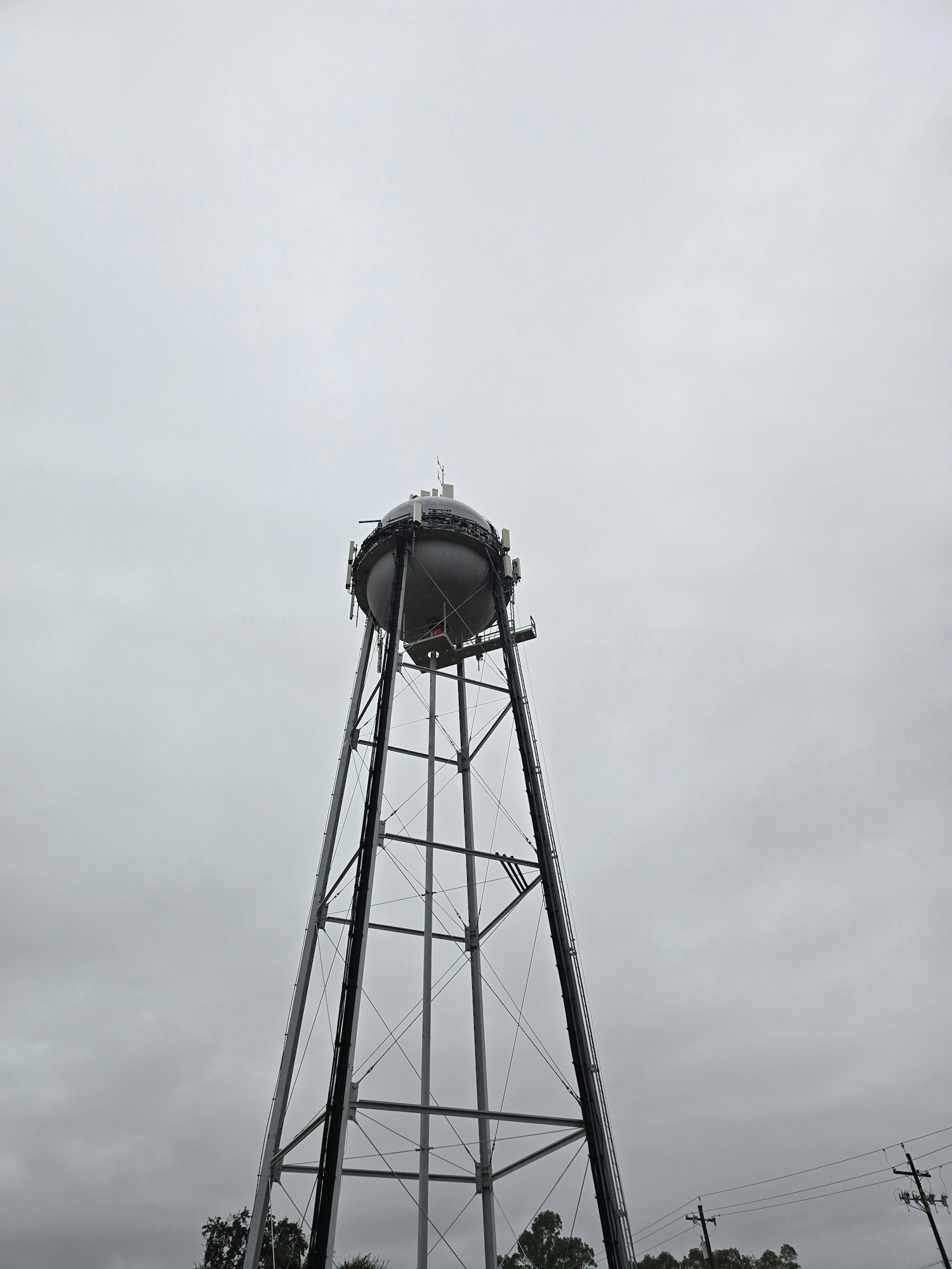 Tall metal water tower against a cloudy sky.