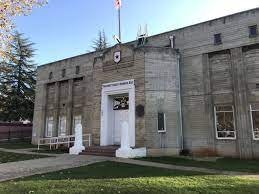 A vintage building with an American flag, lawn in front, clear sky, no people visible.