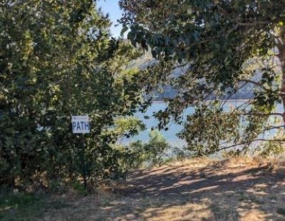 A scenic path sign surrounded by trees, leading to a body of water.