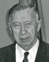 An older man in a suit and tie. The image is black and white.