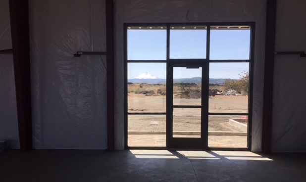 A door and window frame viewing a distant snow-capped mountain in a sunny landscape.
