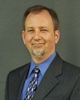 A man in a suit and tie with a gray background.