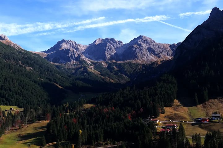 Majestic alpine mountains with forested slopes under a blue sky.