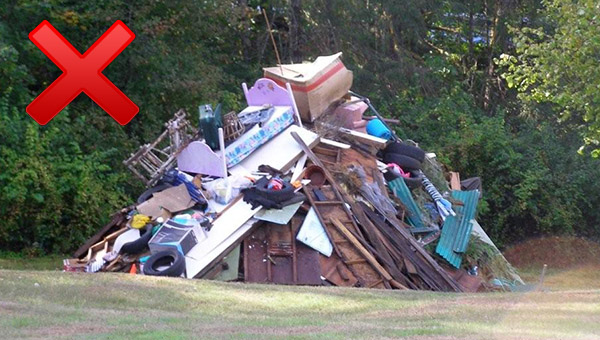 A pile of various discarded items, possibly trash or debris, outdoors with a red "X" sign overlaying the image.