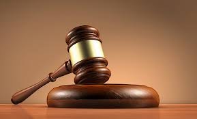 A judge's wooden gavel resting on a sound block.