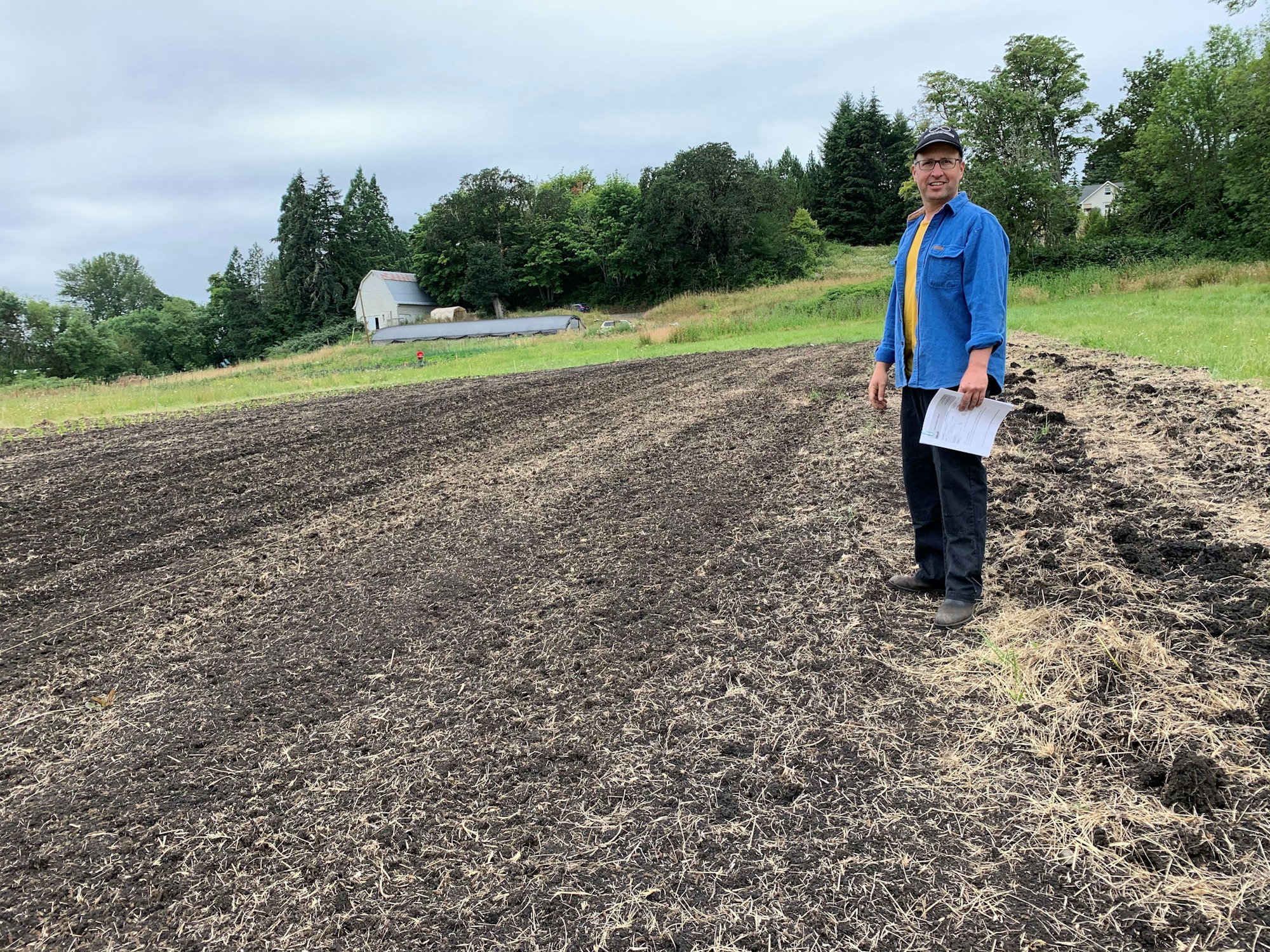 May contain: soil, clothing, pants, plant, tree, person, walking, face, head, photography, portrait, footwear, shoe, standing, vegetation, gravel, road, architecture, building, outdoors, shelter, grass, land, nature, accessories, glasses, hat, field, and fir