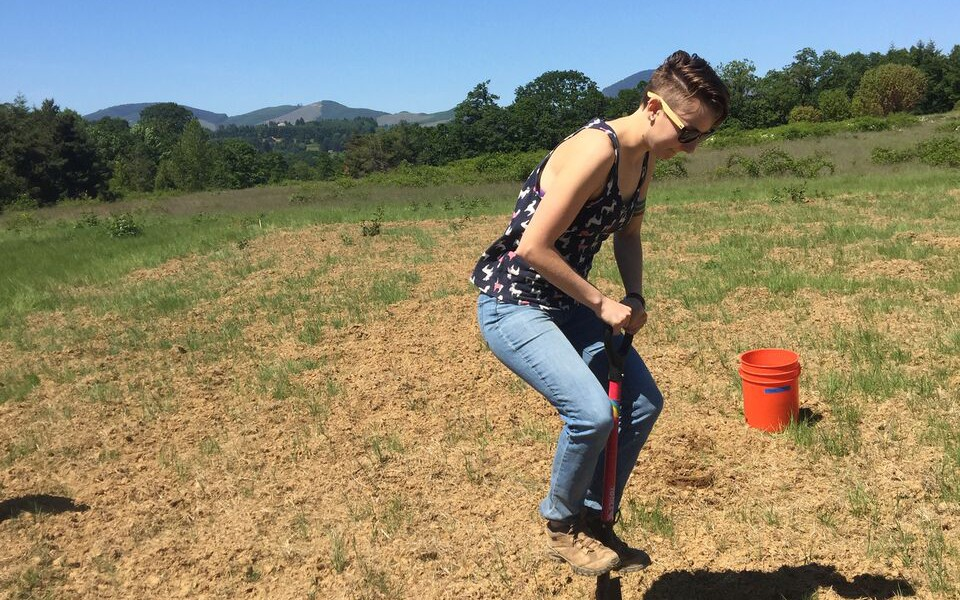 May contain: soil, clothing, pants, grass, plant, face, head, person, photography, portrait, female, girl, teen, jeans, field, vegetation, accessories, glasses, nature, outdoors, tree, footwear, shoe, and bucket