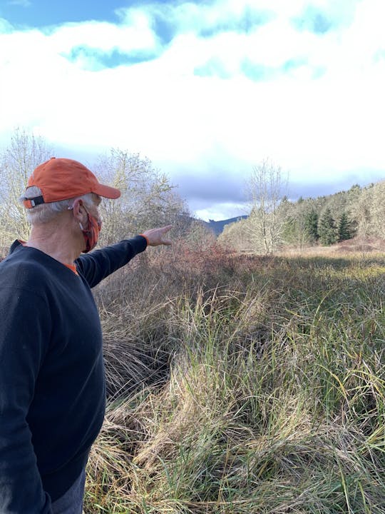 May contain: nature, outdoors, wilderness, cap, clothing, hat, baseball cap, plant, vegetation, grass, face, head, person, photography, portrait, land, soil, tree, woodland, field, grassland, adult, male, man, body part, finger, hand, grove, and sky