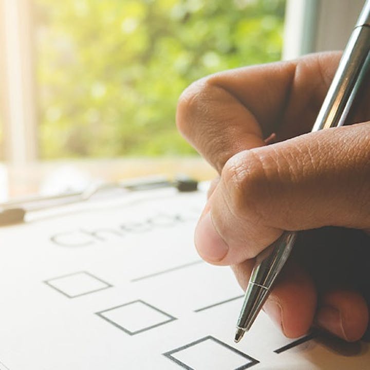 A hand holding a pen, checking boxes on a checklist.