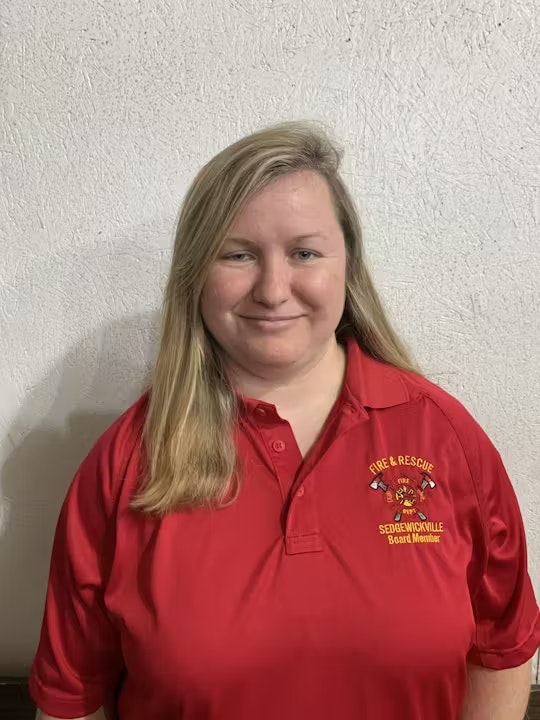 A person wearing a red "Fire & Rescue" shirt standing against a beige wall.
