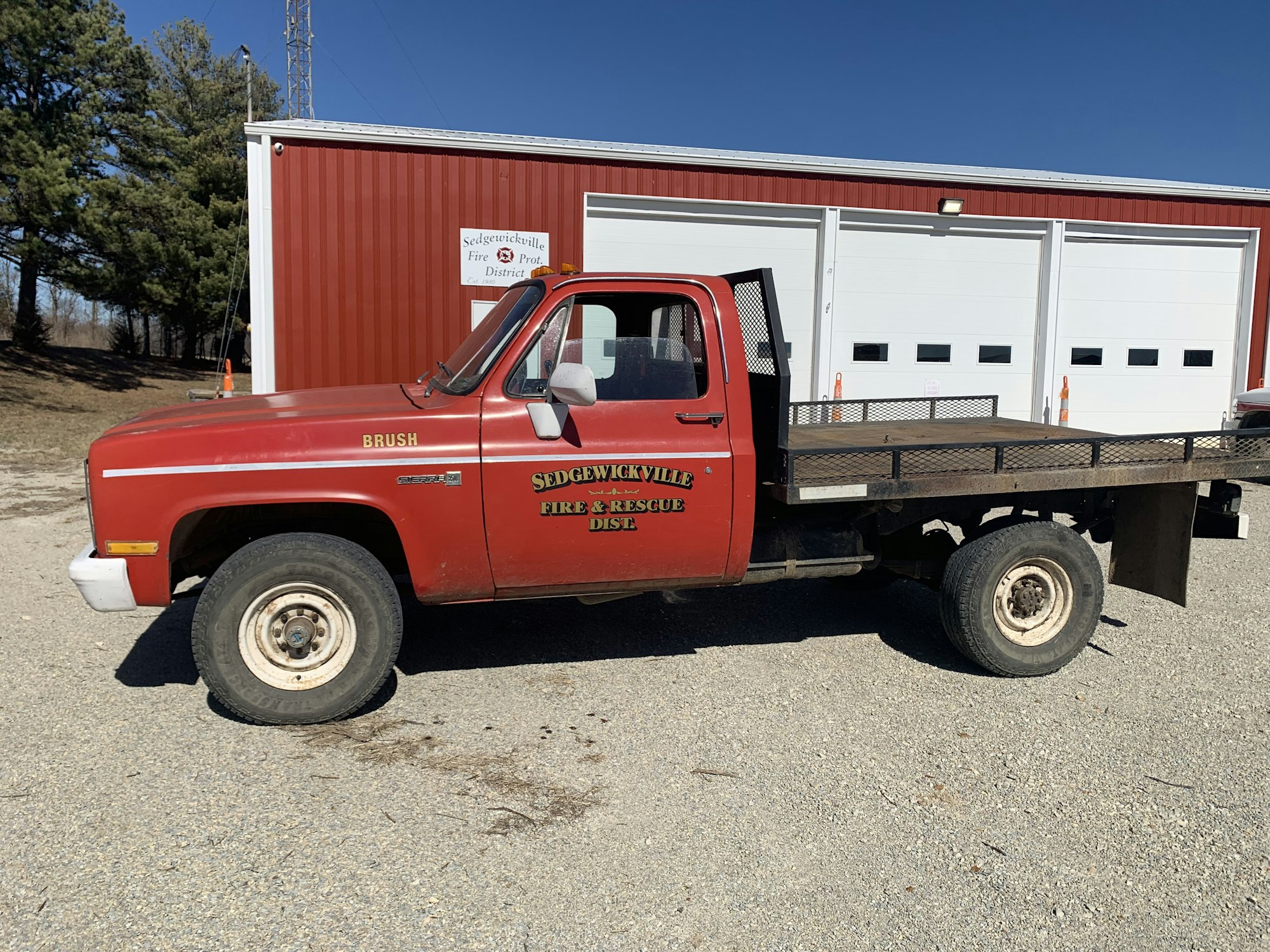 A red fire department utility truck parked outside a building with garage doors.