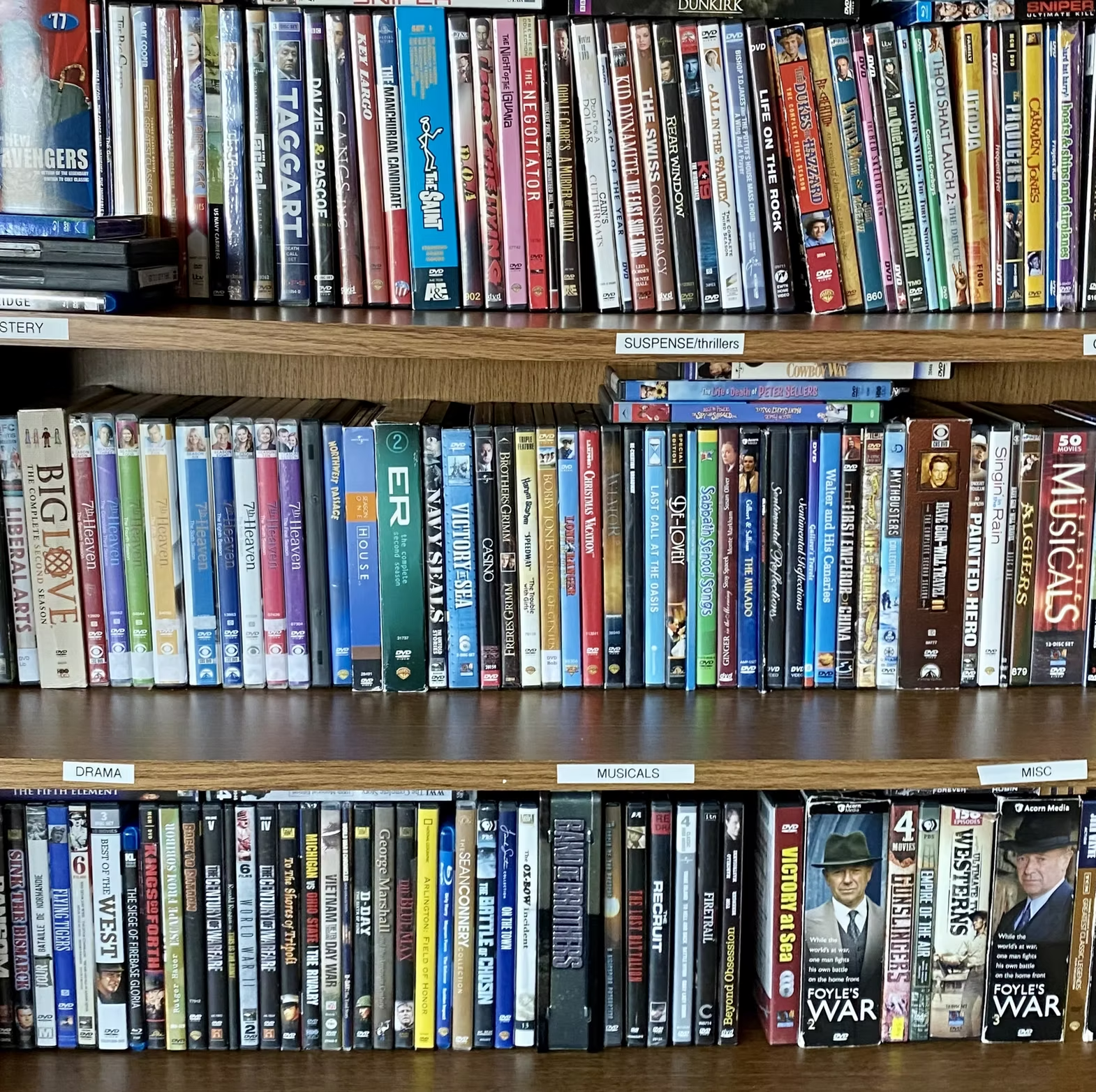 Shelves filled with DVDs organized by genre: mystery, suspense, drama, musicals, and misc. Various titles visible.